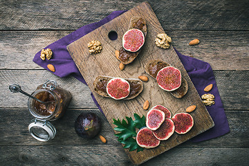 Image showing Cut figs, nuts and bread with jam on wooden choppingboard