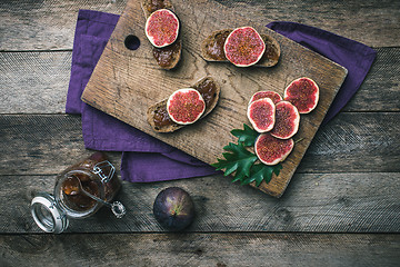 Image showing Cut figs and bread with jam on choppingboard in rustic style