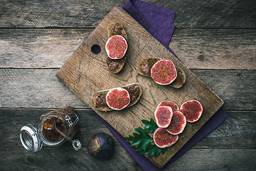 Image showing Sliced figs and bread with jam on choppingboard in rustic style