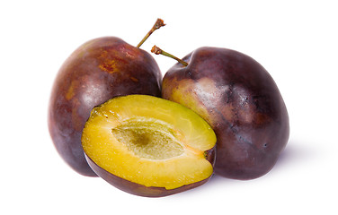 Image showing Two violet plums and half