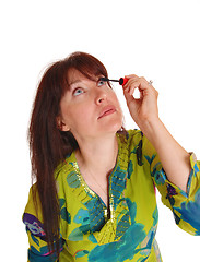 Image showing Woman putting makeup on her eyelashes.