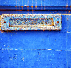 Image showing dirty stripped paint in the blue wood door and rusty nail