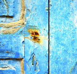 Image showing stripped paint in the blue wood door and rusty nail