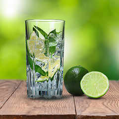 Image showing mohito cocktail on wooden table against green background