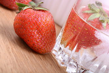 Image showing Strawberry on wooden plate and strawberry frozen in ice cube