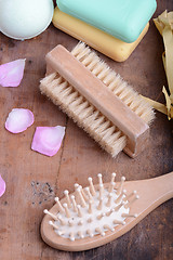 Image showing hair brush, soap, comb, sea salt, spa stones and flower petals on wooden table