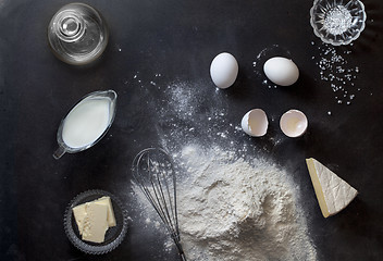 Image showing Dough on black table with flour and ingredients