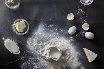 Image showing Dough on black table with flour and ingredients