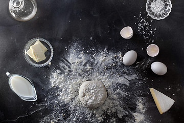 Image showing Dough on black table with flour and ingredients