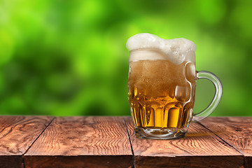 Image showing Beer in glass on wooden table against green