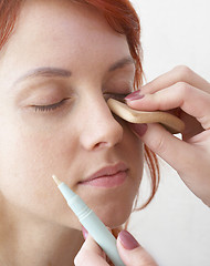 Image showing beautician is doing make-up to red-haired woman