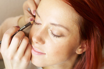 Image showing beautician is doing make-up to red-haired woman