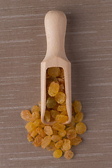 Image showing Wooden scoop with golden raisins