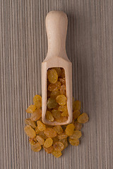 Image showing Wooden scoop with golden raisins