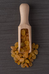 Image showing Wooden scoop with golden raisins