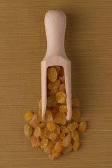 Image showing Wooden scoop with golden raisins