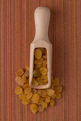 Image showing Wooden scoop with golden raisins