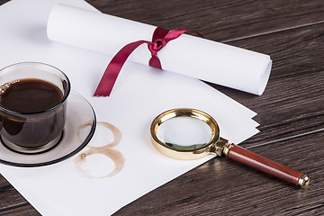 Image showing Coffee cup, paper sheets and detective magnifying glass