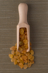 Image showing Wooden scoop with golden raisins