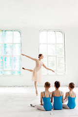 Image showing Three little ballerinas dancing with personal ballet teacher in dance studio