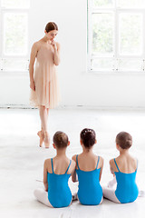 Image showing Three little ballerinas dancing with personal ballet teacher in dance studio