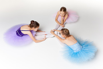 Image showing Three little ballet girls sitting in tutu and posing together