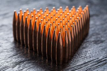 Image showing Macro shot of copper bullets that are in many rows to form a tri