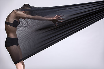 Image showing Slim dancer plays with black mesh fabric