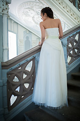 Image showing Elegant bride in a white dress standing on the stairs