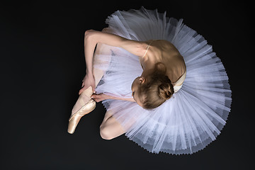 Image showing Young ballet dancer tying pointe sitting on the floor