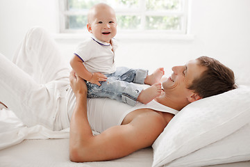 Image showing young father with his nine months old son on the bed at home