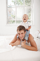 Image showing young father with his nine months old son on the bed at home