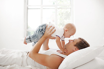 Image showing young father with his nine months old son on the bed at home