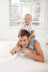 Image showing young father with his nine months old son on the bed at home