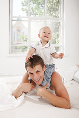 Image showing young father with his nine months old son on the bed at home