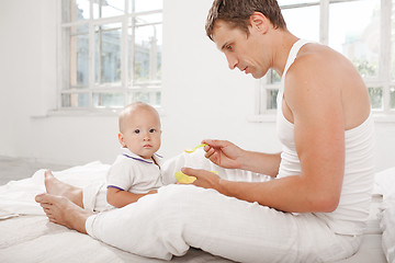 Image showing Young father with his nine months old son on the bed at home