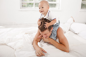 Image showing young father with his nine months old son on the bed at home