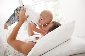 Image showing young father with his nine months old son on the bed at home