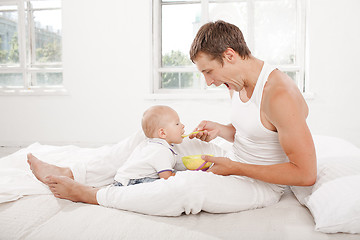 Image showing young father with his nine months old son on the bed at home