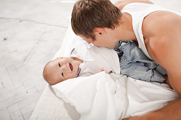 Image showing young father with his nine months old son on the bed at home