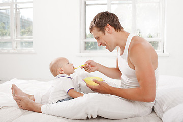 Image showing Young father with his nine months old son on the bed at home