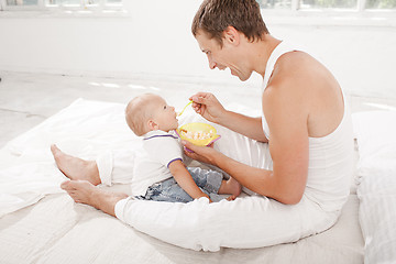 Image showing Young father with his nine months old son on the bed at home