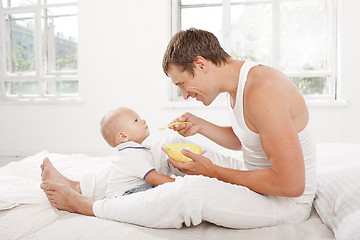 Image showing Young father with his nine months old son on the bed at home