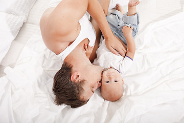 Image showing young father with his nine months old son on the bed at home