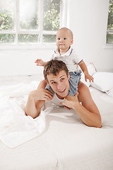 Image showing young father with his nine months old son on the bed at home