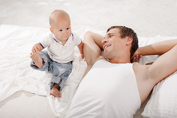 Image showing young father with his nine months old son on the bed at home