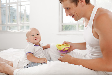 Image showing Young father with his nine months old son on the bed at home