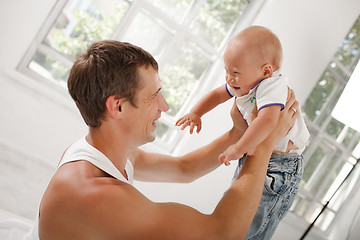 Image showing young father with his nine months old son on the bed at home