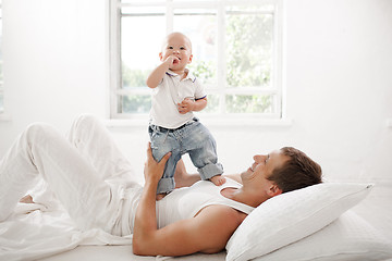 Image showing young father with his nine months old son on the bed at home