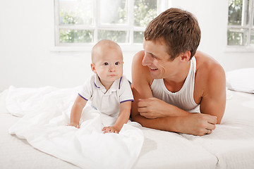 Image showing young father with his nine months old son on the bed at home